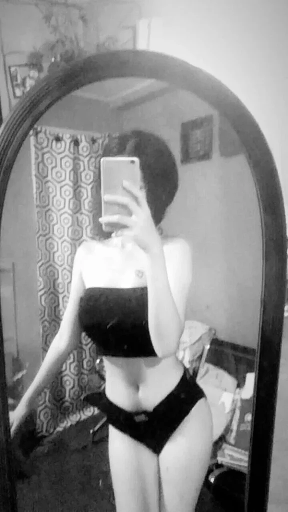 Cô gái chụp gương đen trắng, bikini tối giản, tay che mặt, vai trần nổi bật, dáng đứng rất sang và gợi.