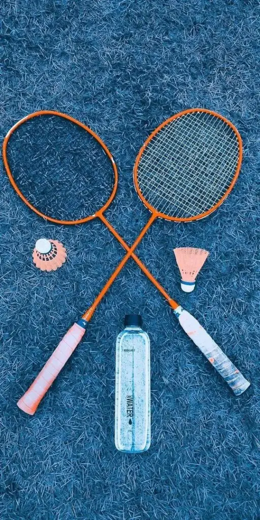 Hình nền hai chiếc vợt gỗ cổ điển đặt chéo nhau trên mặt sàn xanh thẳm làm nổi bật quả cầu lông trắng muốt tạo nên một tổng thể vô cùng hài hòa.