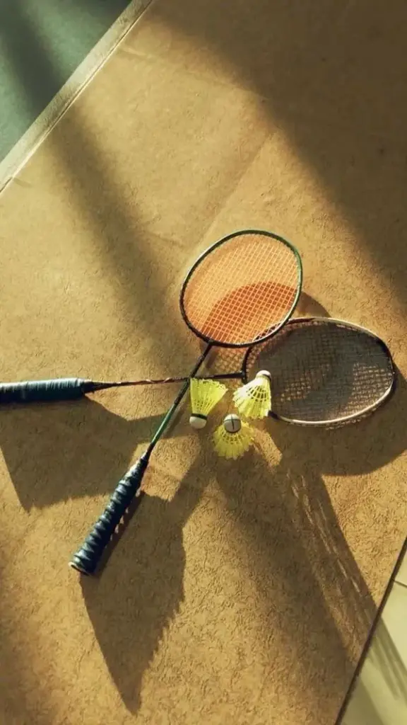 Hình nền thể thao đầy nắng với bóng của chiếc vợt đổ dài trên mặt sân xi măng gợi cảm giác về những buổi tập luyện dẻo dai dưới ánh mặt trời.